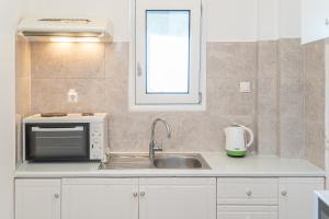a kitchen with a sink and a microwave at Stella Hotel Apartments in Fiskardo