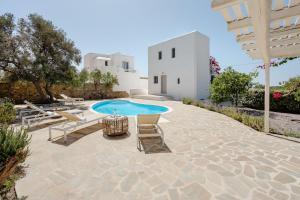 a patio with a pool and chairs and a building at Villa Rocabella Just 100m from Glyfada Beach in Kastraki