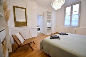 een slaapkamer met een bed, een stoel en een spiegel bij Suite Belleville in Saint-Dizier