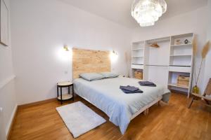 een slaapkamer met een groot wit bed en een kroonluchter bij Suite Belleville in Saint-Dizier +6 foto's