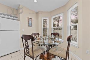Un comedor con mesa y sillas y ventanas. en Legacy Villa 2601, en Gulfport