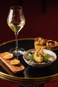 a table with a glass of wine and a plate of food at Le Castel Marie Louise in La Baule