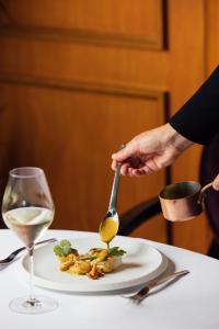 a person holding a spoon over a plate of food at Le Castel Marie Louise in La Baule