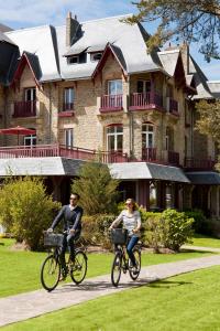 two people riding bikes in front of a large house at Le Castel Marie Louise in La Baule