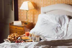 a tray of food on a bed with a breakfast at Le Castel Marie Louise in La Baule