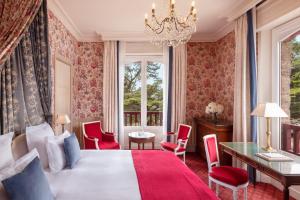 a bedroom with a bed with red chairs and a chandelier at Le Castel Marie Louise in La Baule