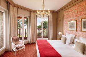 a bedroom with a large bed and a chandelier at Le Castel Marie Louise in La Baule