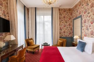 a hotel room with a bed and a chandelier at Le Castel Marie Louise in La Baule