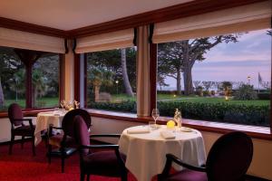 a dining room with tables and chairs and windows at Le Castel Marie Louise in La Baule