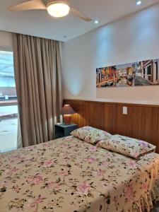 a bedroom with a bed with a floral bedspread at Show de apartamento na Praia do Morro - Guarapari in Guarapari