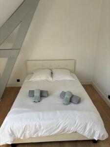 a white bed with three pillows on top of it at Les 4 saisons in Le Touquet-Paris-Plage