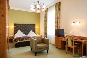 a hotel room with a bed and a desk with a computer at Parkhotel Traunstein in Traunstein