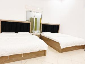 two beds in a room with white walls at Hasy' House-You Jia in Jeddah