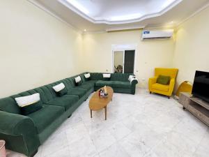 a living room with a green couch and a yellow chair at Hasy' House-You Jia in Jeddah