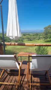 Dos sillas, una mesa y una sombrilla en una terraza. en Cabaña Cielos del Champaqui 6 kms VGB, en Villa Ciudad Parque 2 fotos más