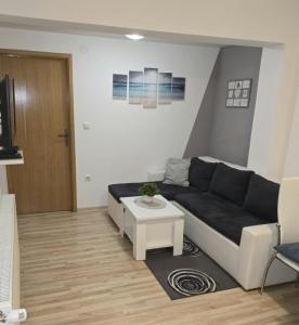 Una sala de estar con un sofá negro y una mesa. en Apartmani Baotić Županja, en Županja 14 fotos más