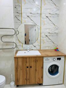 a bathroom with a washing machine and a mirror at Apartments comfort new, Aktau 16 77 in Aktau