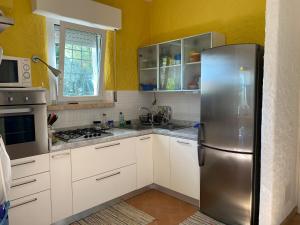 a kitchen with white cabinets and a stainless steel refrigerator at Villa trilocale CON SPIAGGIA E PISCINA incluse - Taunus Vacanze Villa Primule in Numana