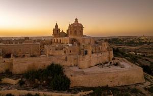 an aerial view of a building with a sunset in the background at The Xara Palace Relais & Chateaux in Mdina