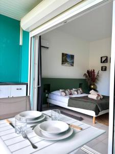 Grand-BourgにあるLa Bulle de Maloma - Piscine, Plage, Espace transat réservéのベッド1台、テーブル(皿付)が備わる客室です。