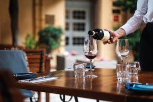 a person pouring wine into two wine glasses on a table at The Xara Palace Relais & Chateaux in Mdina