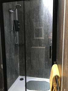 une douche avec une porte vitrée dans une salle de bain dans l'établissement Sefton Cottage, à Ormskirk
