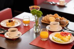 a table with plates of food and cups of orange juice at SANA Capitol Hotel in Lisbon