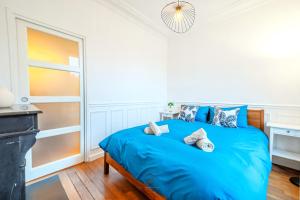 een slaapkamer met een bed met blauwe lakens bij L'Escale Parisienne Charmant T2 proche métro et Paris in Pantin