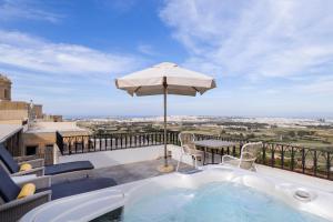 a hot tub on a balcony with an umbrella at The Xara Palace Relais & Chateaux in Mdina