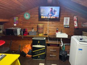 a room with a tv on the wall and a kitchen at Ático com Ar Condicionado Q e F in Ponta Grossa