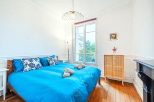 een blauw bed in een kamer met een raam bij L'Escale Parisienne Charmant T2 proche métro et Paris in Pantin