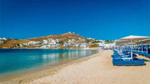 una spiaggia con sedie blu e ombrelloni di Celeste Apartments a Ornos
