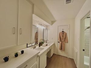 孔洛King Bed Suite in Conroe , Garage Available的浴室设有两个盥洗盆,门廊上挂着一个长袍