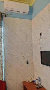 Habitación con pared de azulejos blancos y TV. en HP CLASSIC LODGE Manzese, en Dar es Salaam