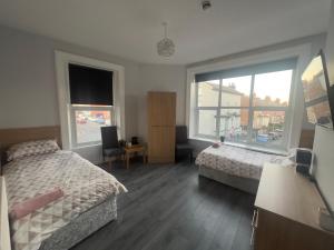 a bedroom with two beds and two windows at The Prince Alfred Rooms in Liverpool