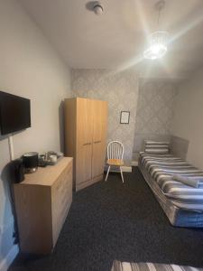a bedroom with a bed and a cabinet and a chair at The Prince Alfred Rooms in Liverpool