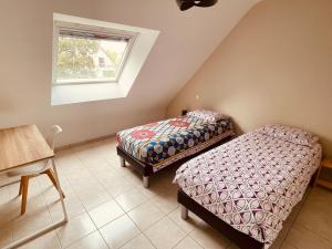two beds in a room with a table and a window at Jolie maison cosy proche plage & cité de la voile in Larmor-Plage