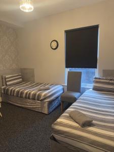 a hotel room with two beds and a chair and a clock at The Prince Alfred Rooms in Liverpool