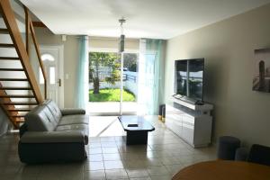 a living room with a couch and a tv at Jolie maison cosy proche plage & cité de la voile in Larmor-Plage