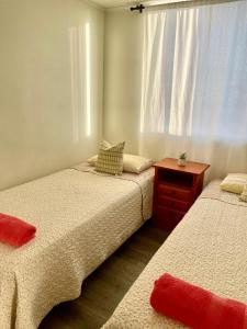 two beds in a room with a window at Departamento 2D en Iquique!!! in Iquique