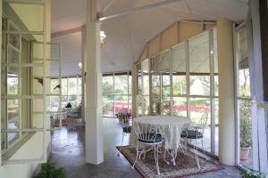a room with a table and chairs and windows at Wathai Heritage Bungalow in Tinsukia