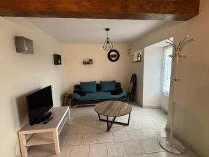 ein Wohnzimmer mit einem blauen Sofa und einem Tisch in der Unterkunft Maison à Boutteville - Proche Ste Mère Eglise in Boutteville