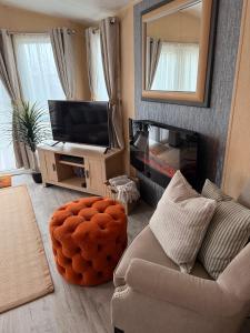 a living room with a couch and a mirror at Stylish Inviting 2 Bedroom Caravan with Sea View in East Mersea