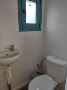 a bathroom with a white toilet and a sink at Tiny Haus Komos in Pitsidia