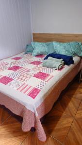 un letto con una trapunta sopra un pavimento di legno di Studio Marangoni Hospedaria Apartamento 2 a Treze Tílias