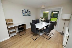 comedor con mesa blanca y sillas negras en Pristine 3 bedroom house, en East Kilbride