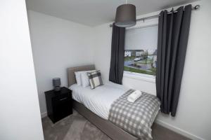 Un dormitorio pequeño con una cama y una ventana. en Pristine 3 bedroom house, en East Kilbride