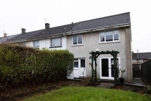 una casa de ladrillo con una puerta blanca y un seto en Pristine 3 bedroom house, en East Kilbride