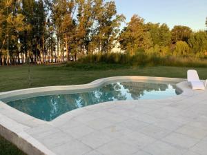a swimming pool in a yard with a chair at Complejos EG in San Miguel del Monte