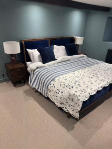 une chambre avec un grand lit avec un mur bleu dans l'établissement Stunning Cotswolds Cottage 5 min from Soho Farmhouse, à Enstone